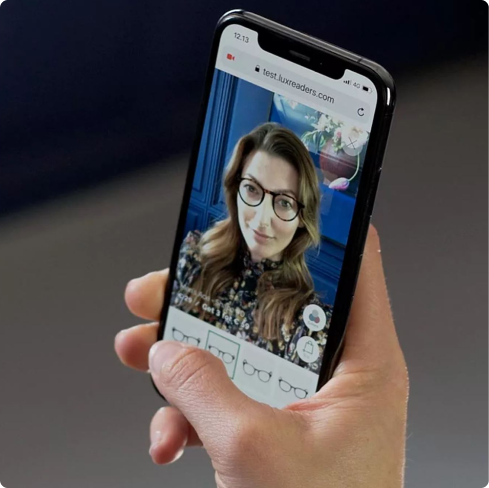 Brünette Frau ist auf Smartphone zu sehen mit virtueller Lesebrille von Luxreaders.