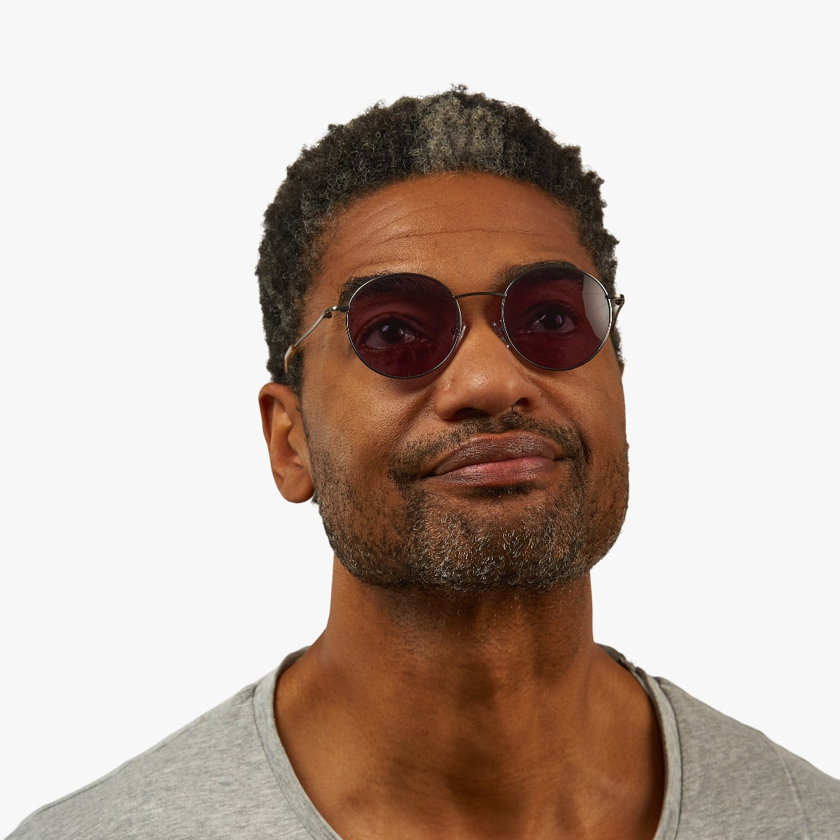 Person wearing round sunglasses with dark lenses and metal frame